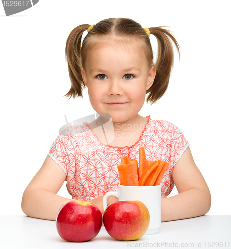 Image of Cute little girl eats carrot and apples