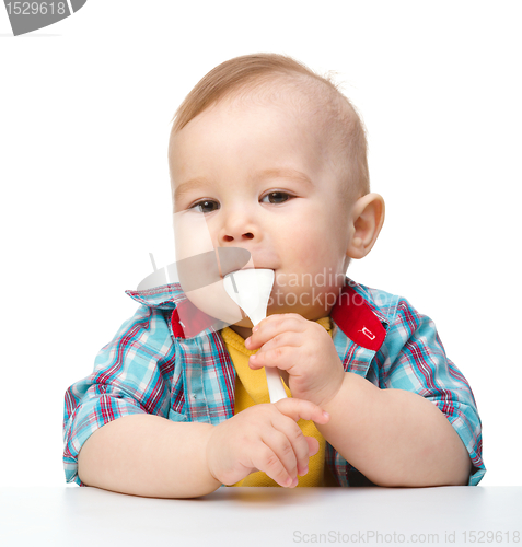 Image of Cute little boy is biting spoon