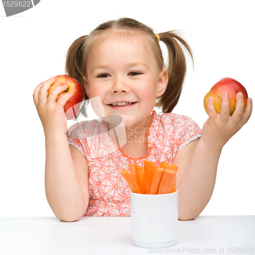 Image of Cute little girl eats carrot and apples