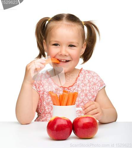 Image of Cute little girl eats carrot and apples