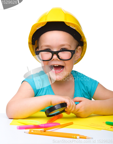 Image of Cute little girl is playing while wearing hard hat