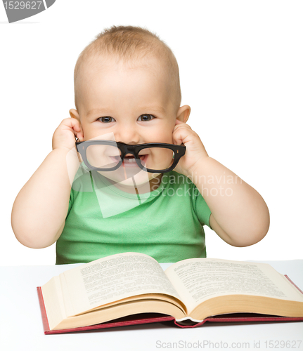 Image of Little child play with book and glasses