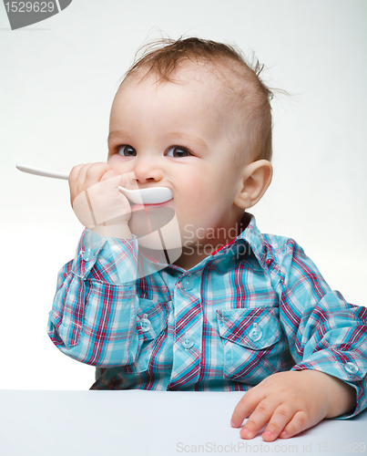 Image of Cute little boy is biting spoon