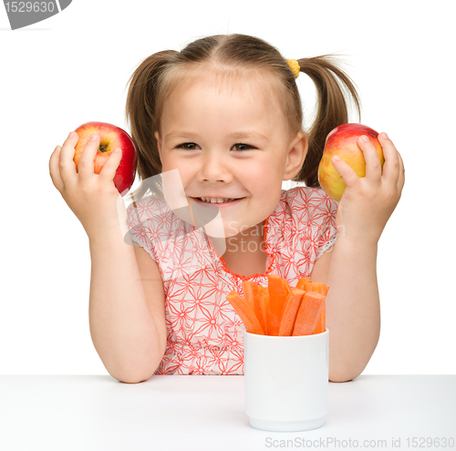 Image of Cute little girl eats carrot and apples