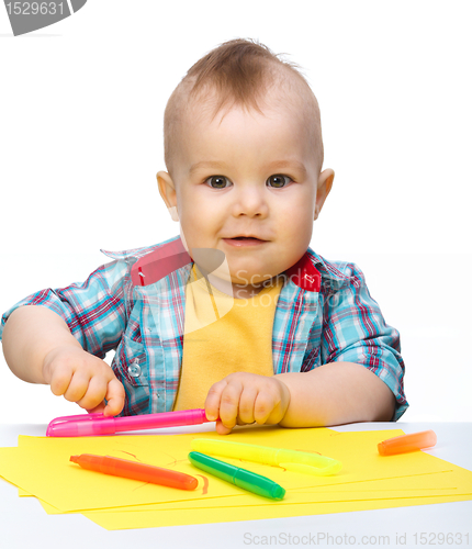 Image of Happy little boy is playing with colorful markers