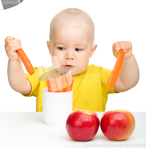 Image of Little boy pulling up carrot from a cup