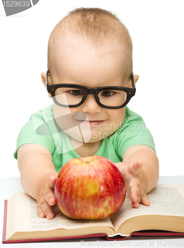 Image of Little child is playing with red apple