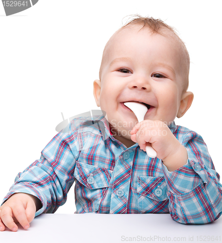 Image of Cute little boy is biting spoon
