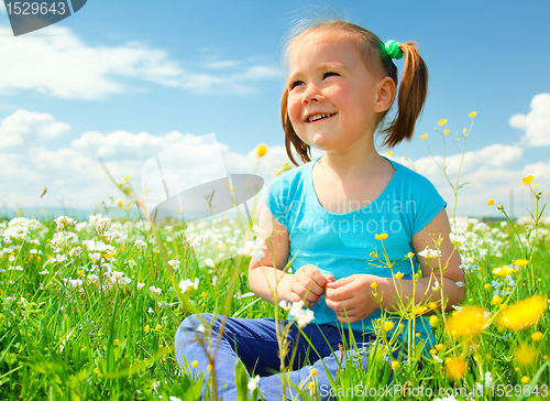 Image of Little girl is playing on green meadow