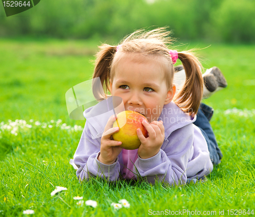 Image of Little girl is laying on green meadow