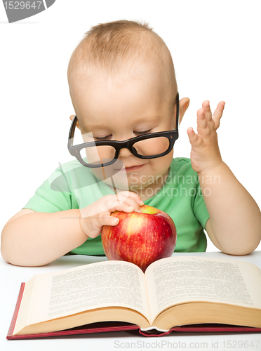 Image of Little child is playing with red apple