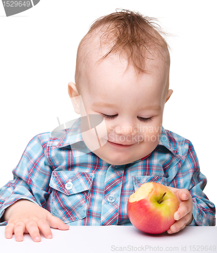 Image of Little child is eating red apple