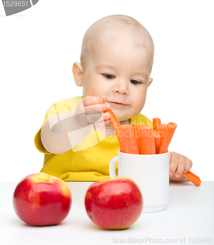 Image of Little boy pulling up carrot from a cup
