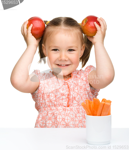 Image of Cute little girl eats carrot and apples