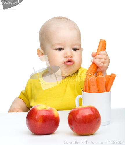Image of Little boy pulling up carrot from a cup