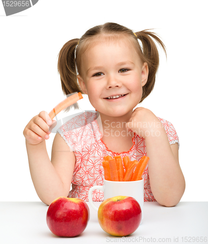 Image of Cute little girl eats carrot and apples