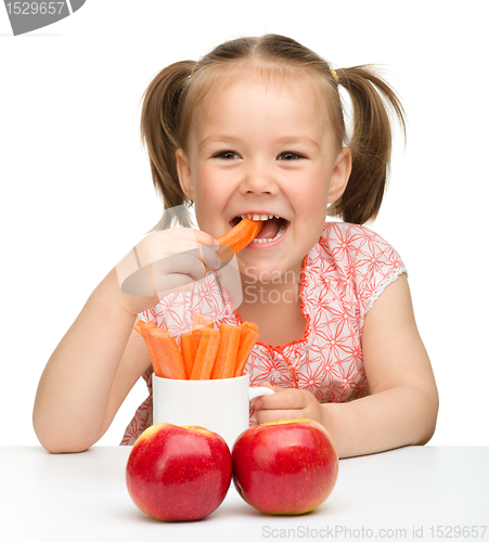 Image of Cute little girl eats carrot and apples
