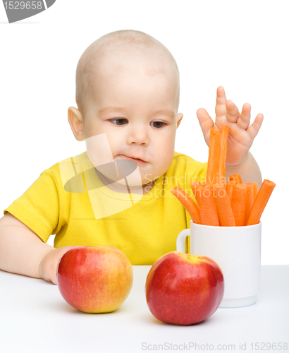 Image of Little boy pulling up carrot from a cup