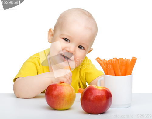 Image of Cute little boy eats carrot and apples