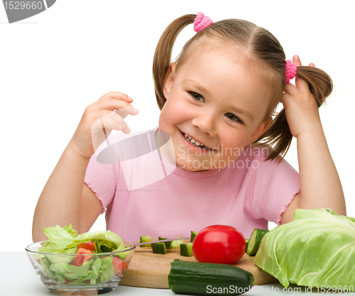 Image of Little girl is cutting carrot for salad