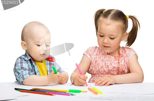 Image of Two children are drawing on paper using markers