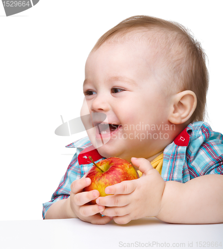 Image of Little child is eating red apple and smile