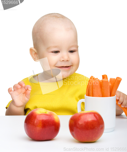 Image of Cute little boy eats carrot and apples