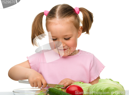 Image of Little girl is cutting carrot for salad