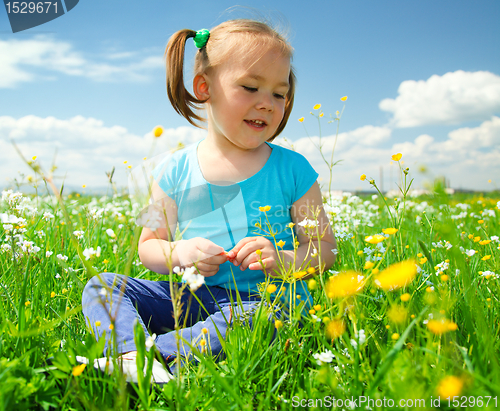Image of Little girl is playing on green meadow