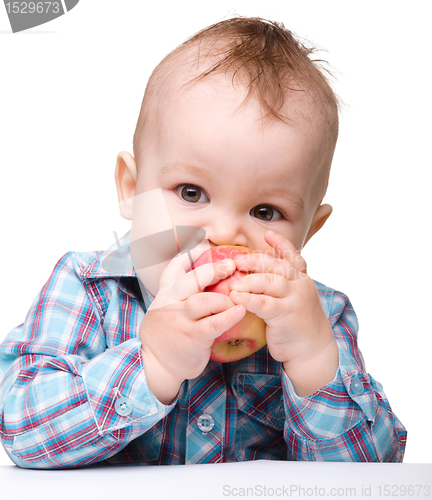 Image of Little child is biting red apple and smile