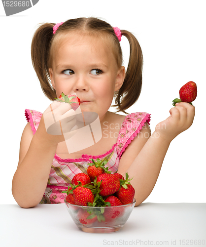 Image of Happy little girl eats strawberries
