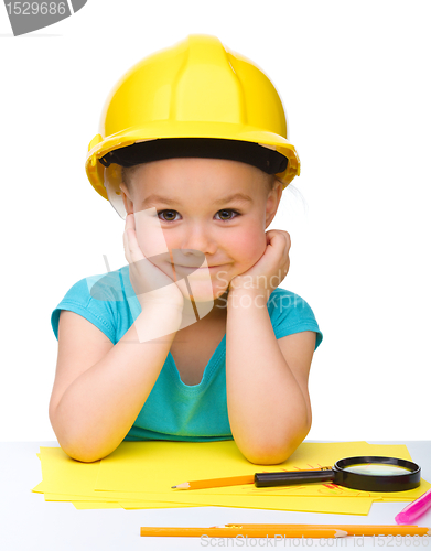 Image of Cute little girl is playing while wearing hard hat