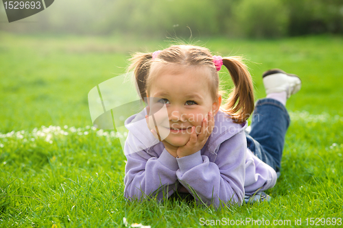 Image of Little girl is laying on green meadow