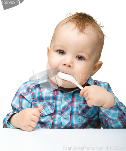 Image of Cute little boy is biting spoon