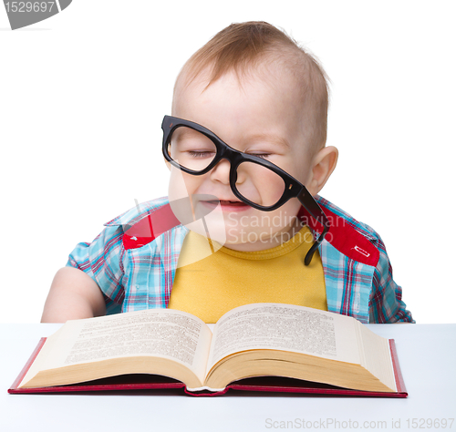 Image of Little child play with book and glasses