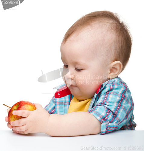 Image of Little child is eating red apple