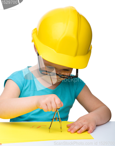 Image of Little girl is playing while wearing hard hat