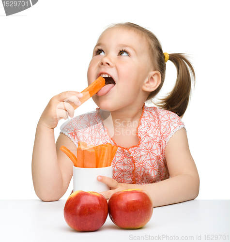 Image of Cute little girl eats carrot and apples