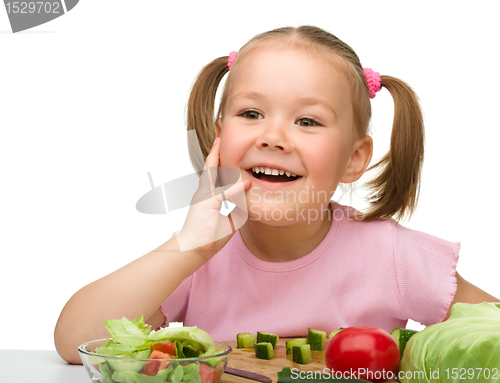 Image of Little girl is cutting carrot for salad
