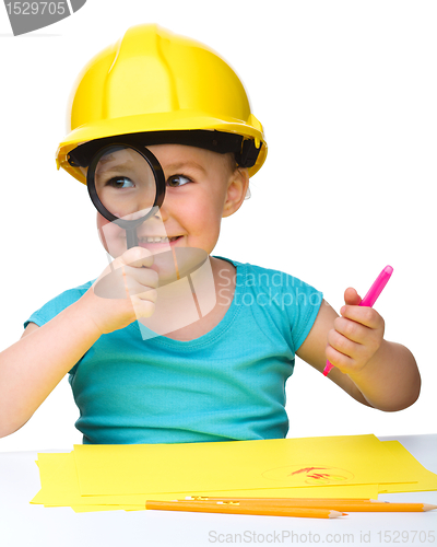 Image of Cute little girl is looking through magnifier