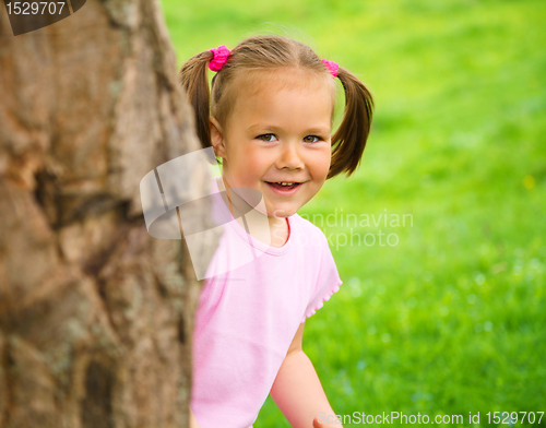 Image of Little girl is playing hide and seek outdoors