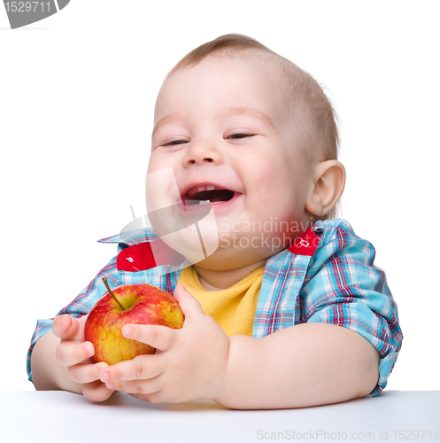 Image of Little child is eating red apple and smile