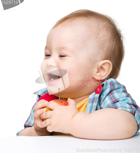 Image of Little child is eating red apple and smile