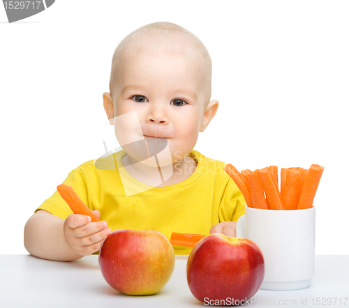 Image of Cute little boy eats carrot and apples