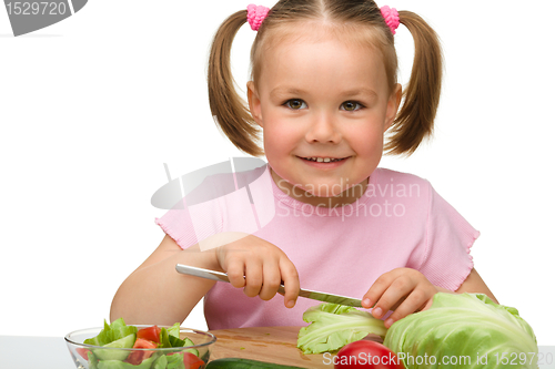 Image of Little girl is cutting carrot for salad