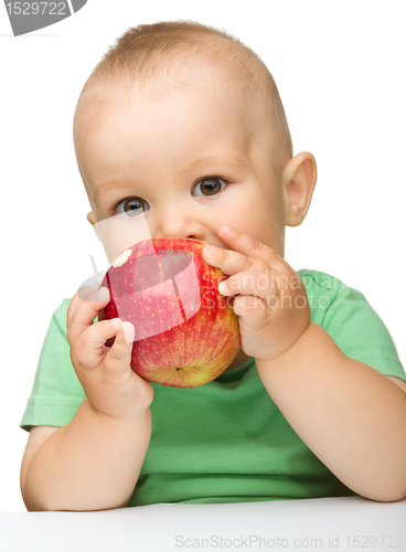 Image of Little child is eating red apple