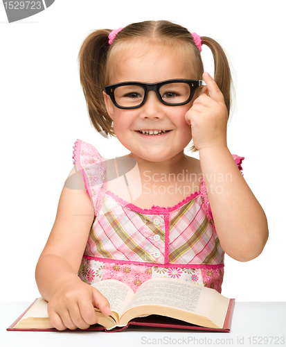 Image of Little girl is flipping over pages of a book