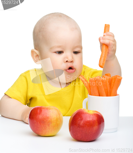 Image of Little boy pulling up carrot from a cup