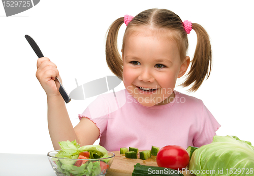 Image of Little girl is cutting carrot for salad
