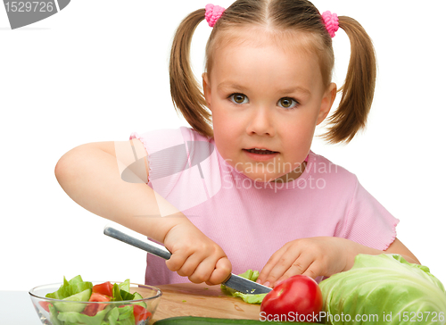 Image of Little girl is cutting carrot for salad